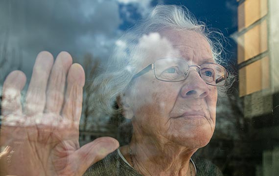 elderly woman standing behind glass door