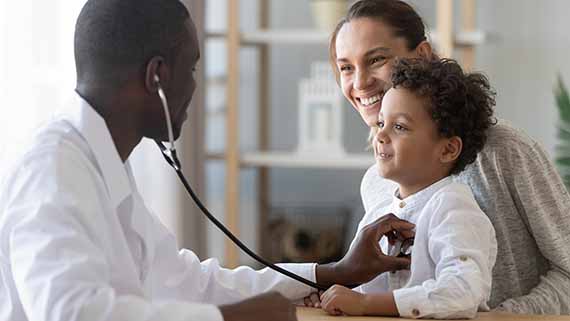 Doctor checking on a child's heart rate with a stethoscope. This child is accompanied by his mother.