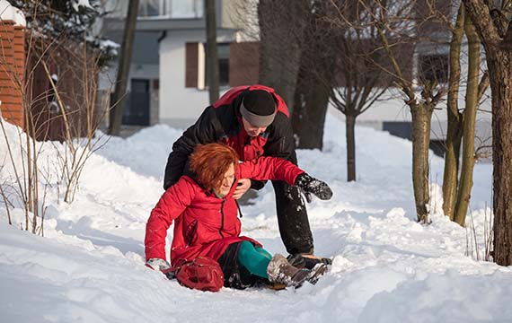 a woman receives assistance getting up after falling in snow