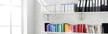 Two shelves of file organizers and books